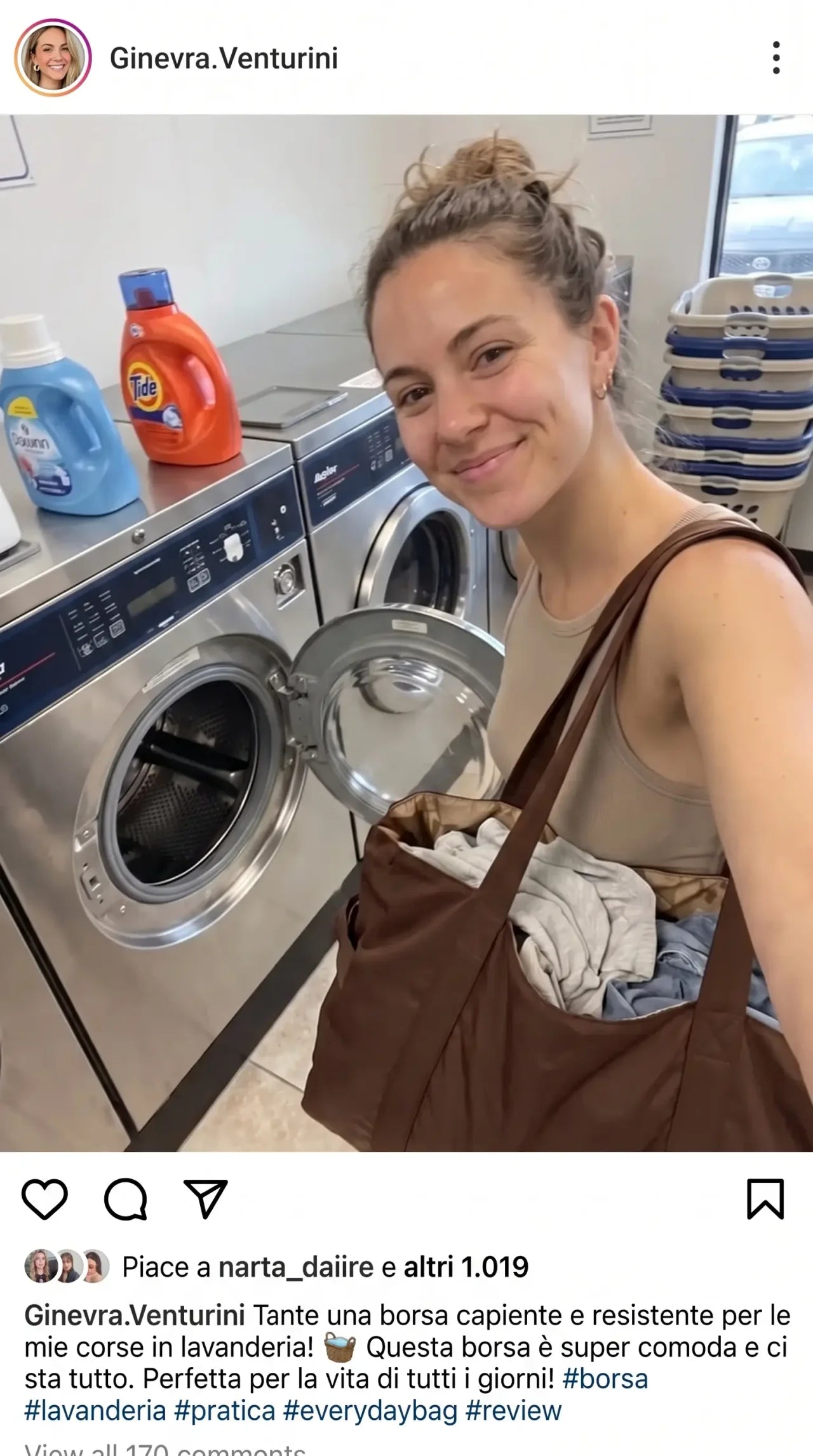 Cliente in lavanderia con la Colette Bag marrone piena di panni davanti alla lavatrice